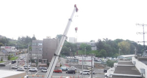 足場用の鉄パイプをクレーンで屋上に引き上げます